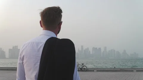 A man walking with a suit by the river in Qatar Stock Footage 86739666