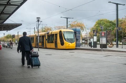 Man walking with suitcase in front of the train station Stock Photos