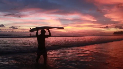 A man is walking with a surf in his hands across the sea shore. Stock Footage 80936734