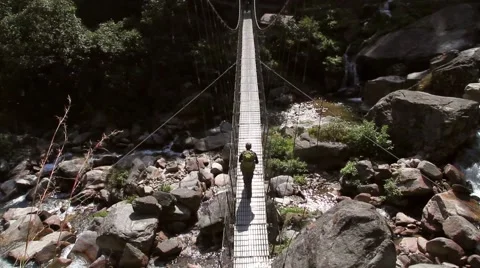 Man walking on suspension bridge Stock Footage 62388630