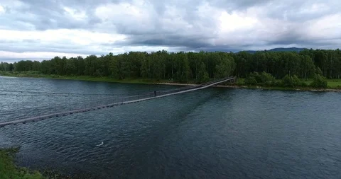 Man walking on a suspension bridge over a mountain river Vídeo Stock 112929437