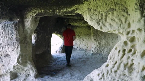 Man walking through ancient stone cave 動画素材 308193705