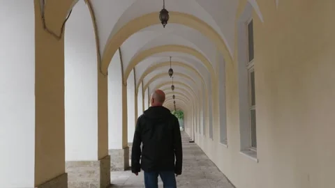 Man walking through arched colonnade corridor with hanging lanterns Stock Footage 339488917