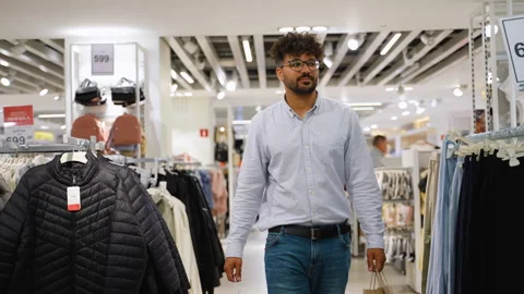 Man walking through clothing store holding shopping bag Stock Footage 314027477