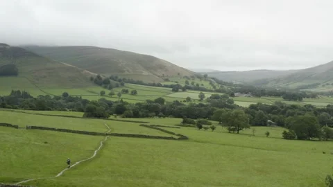 A man walking through a cloudy rural landscape aerial Stock Footage 135057361