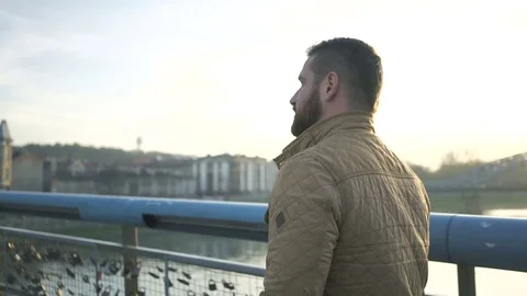 Man walking through the footbridge over river, looking around, profile steadycam 库存影片 72775684