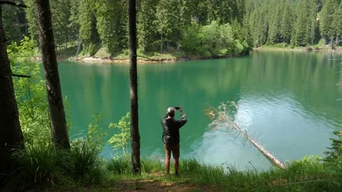 Man walking through the forest on the shore of the mountain lake. Stock Footage 156719370
