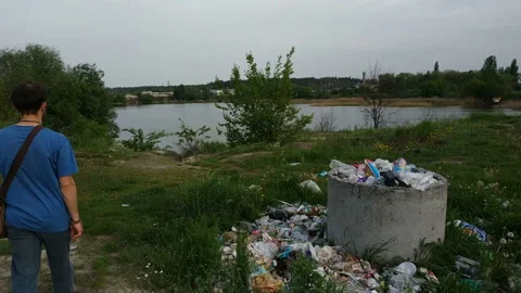 A man walking through garbage at forest near lake. Stock Footage 157101798