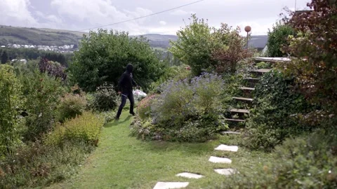 Man Walking Through Hillside Garden, Panoramic Valley View, Wide Shot Video stock 341526925