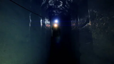 Man walking through ice tunnel discovering glacier cave using a flashlight Stock Footage 64802384