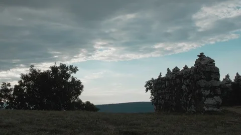 Man walking through a meadow with stone towers on an overcast and sunny day Stock Footage 121807222