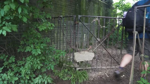 A man walking through a rural gate with rock closing system 動画素材 135060457