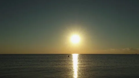 Man walking through shallow water at sunriseas airplane crosses the sun Stock Footage 326507912