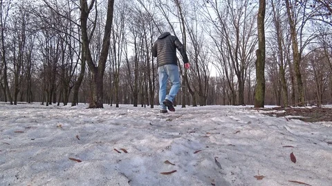 Man walking through a snowy park on a winter day, talking by mobile phone. Video stock 102425614