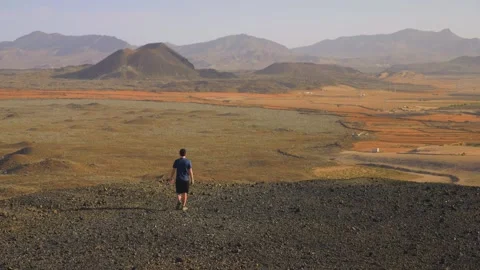 Man walking through volcanic landscape wide scenic view 스톡 동영상 331194539