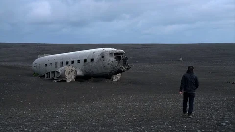 Man walking toward abandoned plane in Iceland Видео 72332202