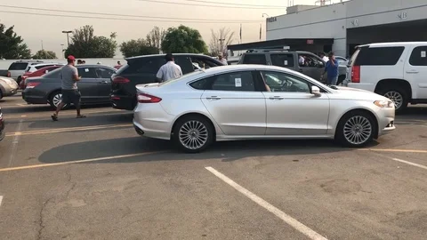 Man walking towards building looking at cars at car auction Vídeos de archivo 100793777