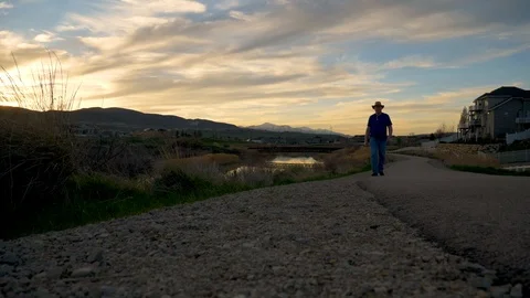 Man walking towards the low angle camera with sunset in the background Stock Footage 106738446