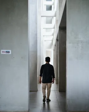 A man is walking towards somewhere between the minimalist walls Stock Photos
