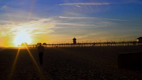 Man walking towards sunset on beach, 4K Stock Footage 101002338