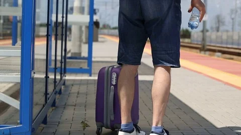 Man walking on the train station with his luggage and water Stock Footage 78653394