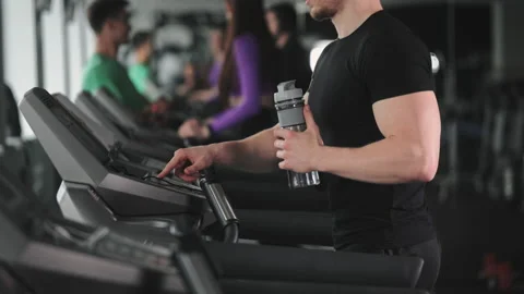 A man is walking on a treadmill and choosing a training program. He is holding a Stock Footage 168809667