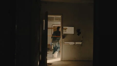 Man walking under orange tape in doorway in empty room Stock Footage 275702109