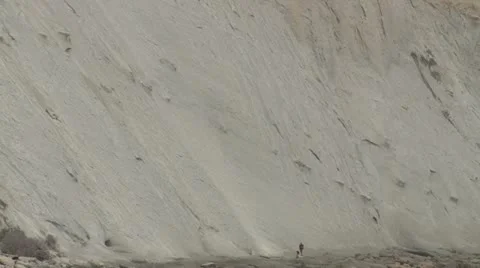 Man walking under sedimentary cliffs Stock Footage 22392573