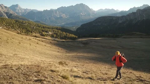 Man walking uphill with backpack and Dolomite Alps Stock Footage 201165110