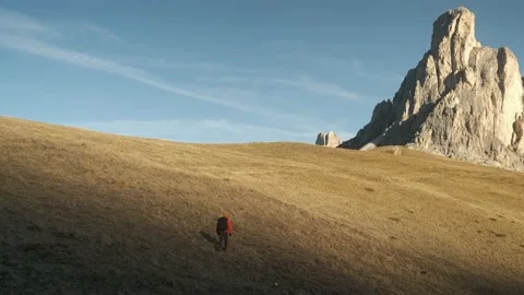 Man walking uphill with backpack and Dolomite Alps Stock Footage 201165112