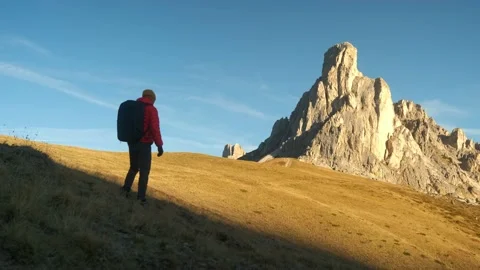 Man walking uphill with backpack and Dolomite Alps on the background. Video stock 201165113