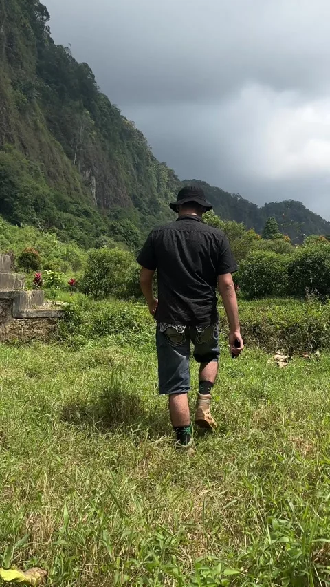Man Walking Uphill Through Grass to Stone Steps in Green Mountains Vertical Video stock 323912828