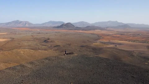 Man Walking on Volcanic Ridge Over Vast Landscape Fuerteventura 스톡 동영상 331312546
