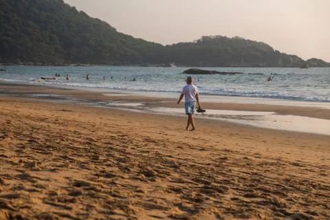 Man walking in waves on beach Foto stock