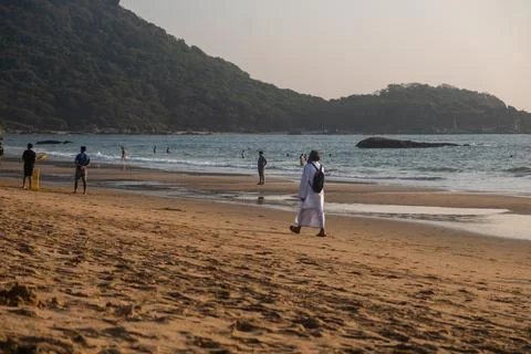 Man walking in waves on beach Stock Photos