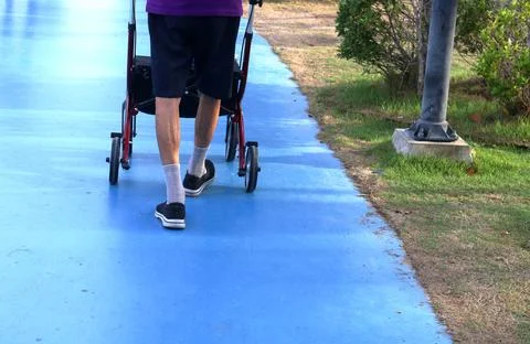 Man walking with wheeling walker on path. Stock Photos