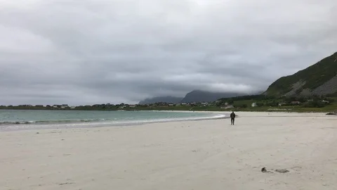 A man walking on the white beach of Ramberg, Lofoten islands, Norway Stock-Footage 128004775