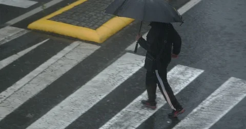 Man walking in a zebra crossing during a heavy storm Video stock 123365955