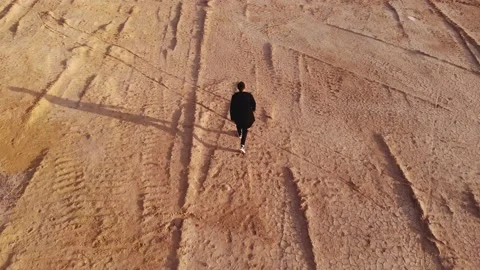 A man walks across a bare field. the drone flies after the person. Stock Footage 166399700