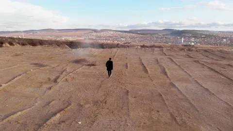 A man walks across a bare field. the drone flies after the person. Stock Footage 166399880