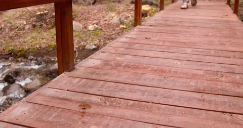 Man walks across bridge by stream Stock Footage 132345035