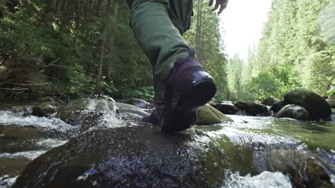 A man walks across a mountain river, leg close-up, summer, green forest Stock Footage 236305094