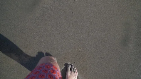 A man walks along the beach in the frame only legs top view sand and waves 库存影片 126969914