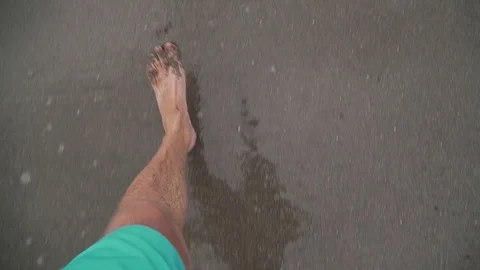 A man walks along the beach in the frame only legs top view sand and waves Stock Footage 126970439