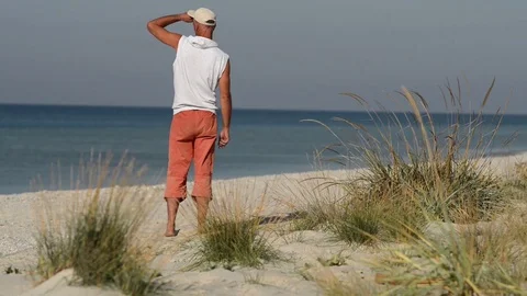 Man walks along the beach on a sunny windy day Stock Footage