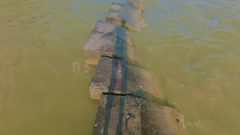 A man walks along the breakwaters with small wave impacts. 库存影片 339311136