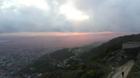 Man walks along canyon path against city and evening sky Stock Footage 131045000