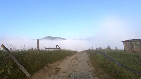 Man walks along dirt path on mountaintop, under which there is morning fog Stock Footage 141823456