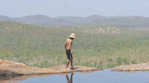 Man walks along the edge of the cliff at Gunlom Falls, Kakadu Stock Footage 68939635