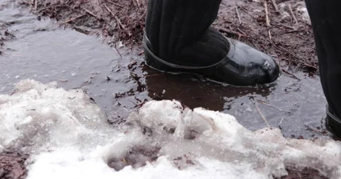A man walks along a flowing stream in the slush Stock Footage 150397331